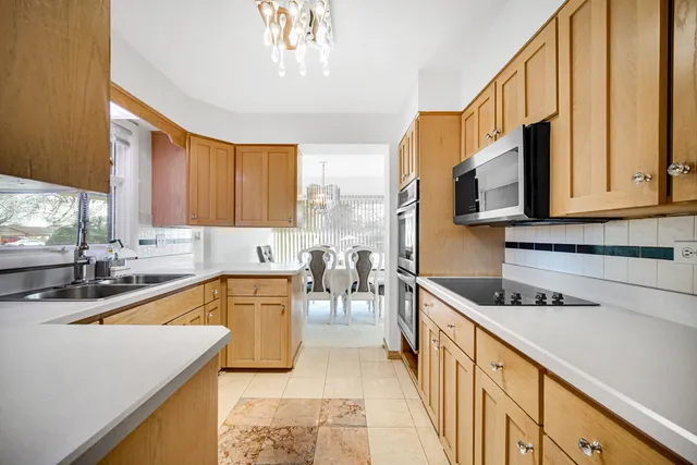 a kitchen with stainless steel appliances granite countertop a sink a stove cabinets counter space and a window