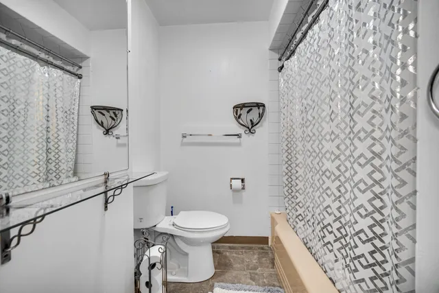a white toilet sitting next to a shower curtain