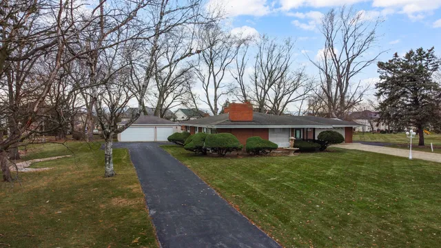 a view of a house with a yard and a large tree