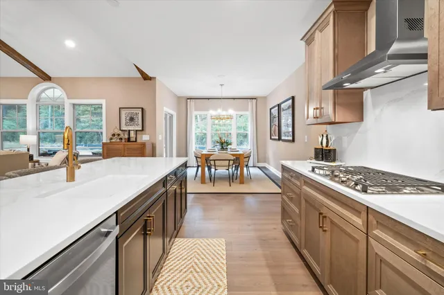 a kitchen with stainless steel appliances granite countertop a stove a sink dishwasher a dining table and chairs with wooden floor