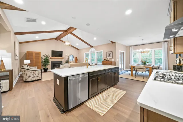 a open kitchen with stainless steel appliances granite countertop a stove top oven a sink dishwasher and a fireplace with wooden floor