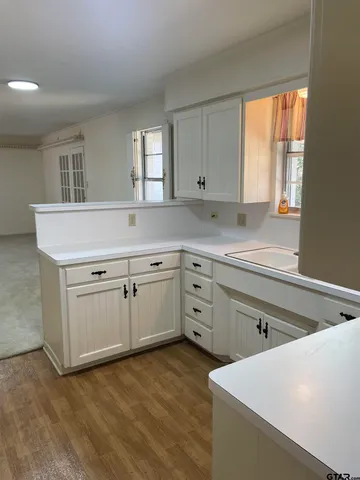 a kitchen with white cabinets and window