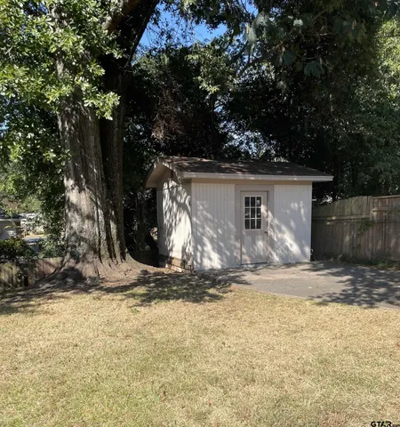 a view of a barn house next to a yard with large trees