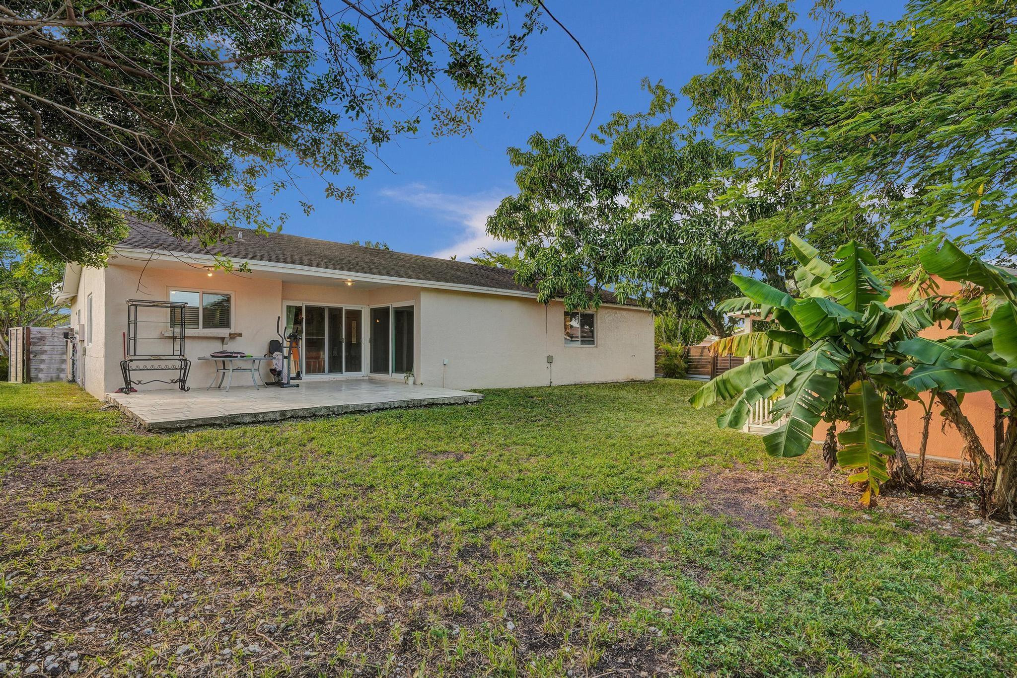 26205 Southwest 133rd Court Homestead, FL 33032 - Photo 11 of 45 a backyard of a house with table and chairs under an umbrella