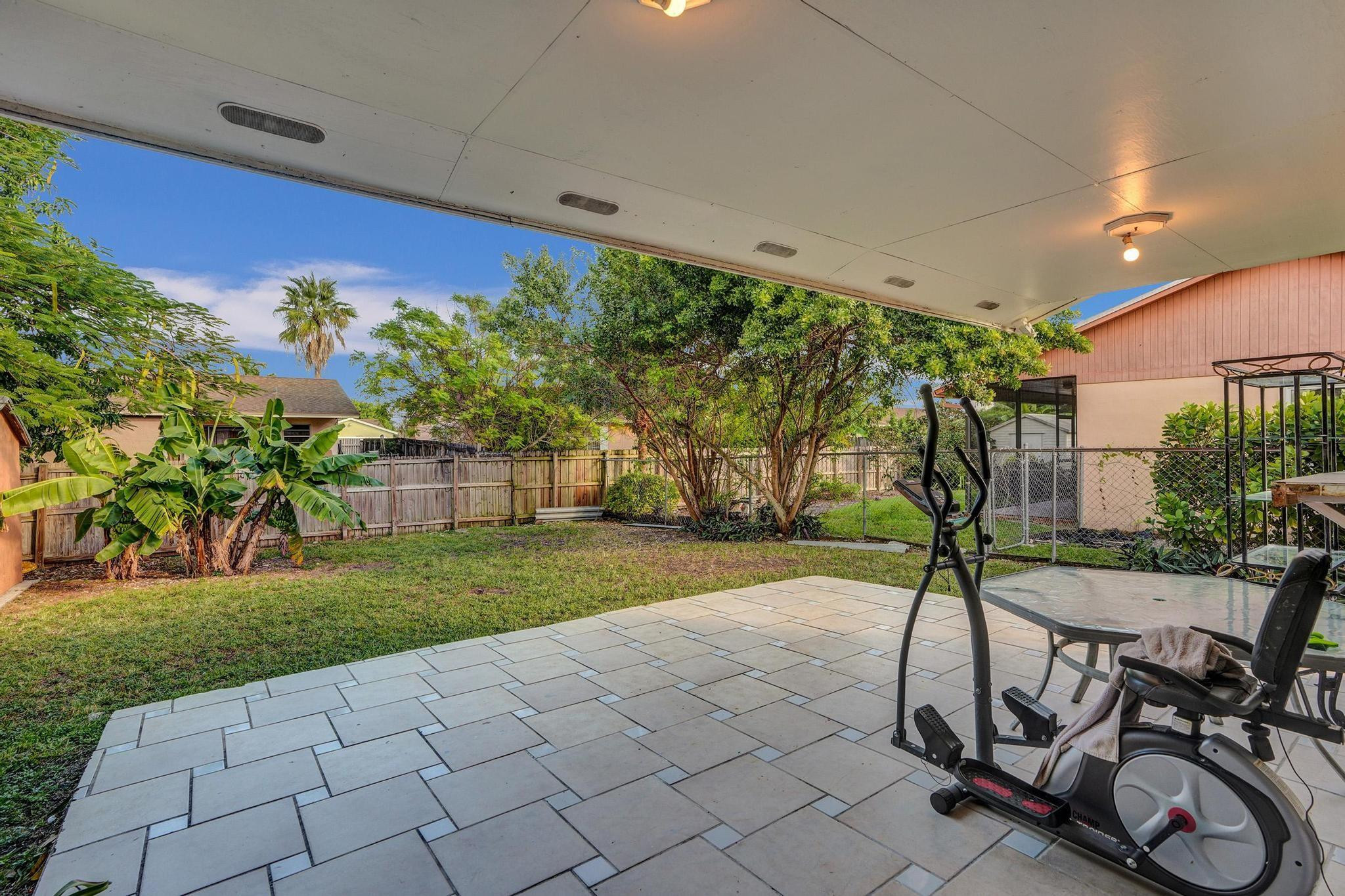 26205 Southwest 133rd Court Homestead, FL 33032 - Photo 14 of 45 a view of a backyard with table and chairs potted plants and a palm tree
