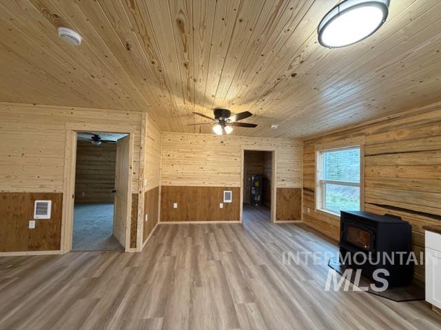 124 Windmill Lane Kooskia, ID 83539 - Photo 19 of 50 Bonus room with a wood stove, wood walls, light wood-style flooring, and a ceiling fan