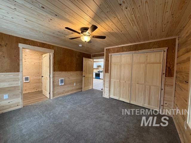 124 Windmill Lane Kooskia, ID 83539 - Photo 19 of 47 Unfurnished bedroom featuring wooden walls, dark colored carpet, a ceiling fan, ensuite bath, and a closet