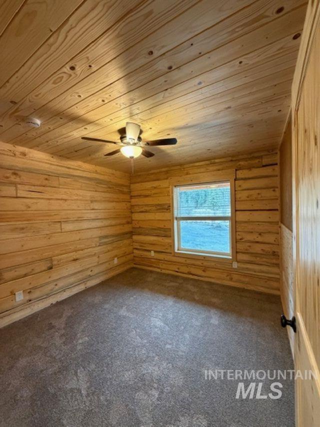 124 Windmill Lane Kooskia, ID 83539 - Photo 26 of 47 Unfurnished room featuring wood walls, dark carpet, and wood ceiling