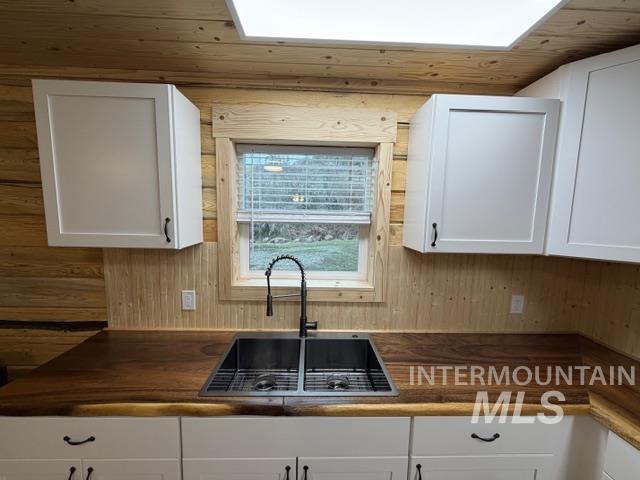 124 Windmill Lane Kooskia, ID 83539 - Photo 10 of 47 Kitchen with white cabinetry, a skylight, and wooden walls