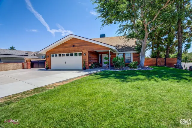 a front view of a house with a garden and trees