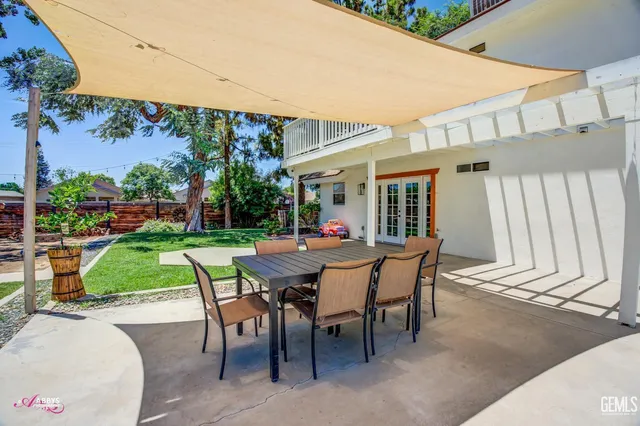 a view of a white house with a yard and table and chairs under an umbrella