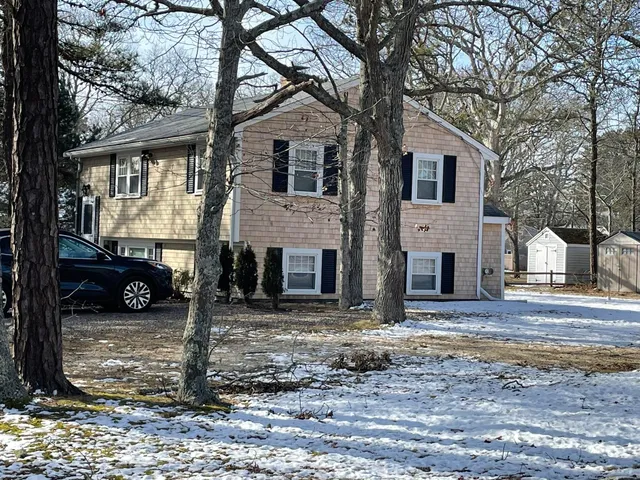 a view of a white house with large tree and wooden fence