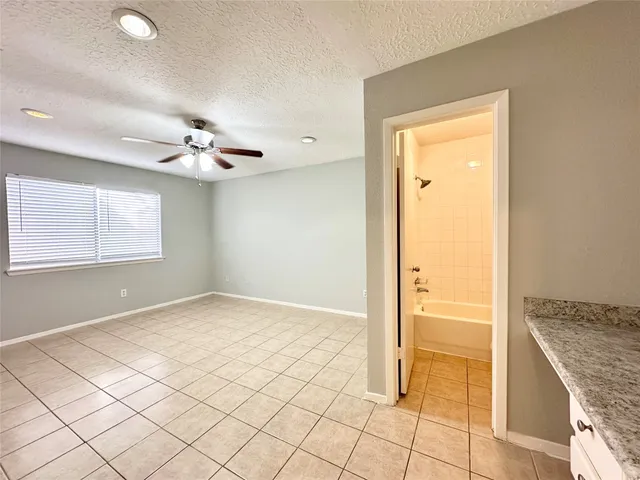 an empty room with kitchen view and windows