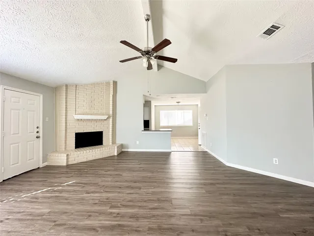 a view of a livingroom with a fireplace a ceiling fan and wooden floor