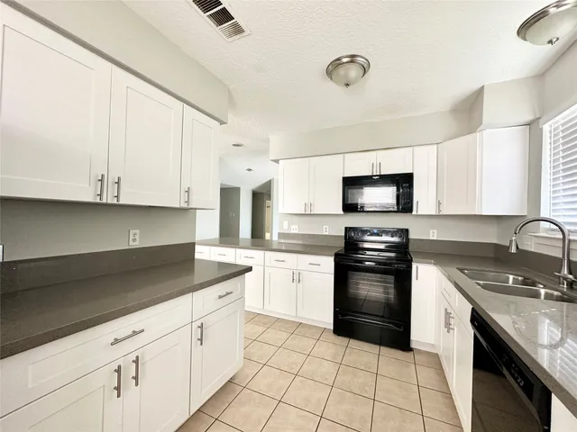 a kitchen with granite countertop white cabinets stainless steel appliances and a sink