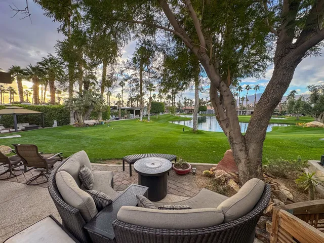 a view of a swimming pool and lounge chairs in back of the house