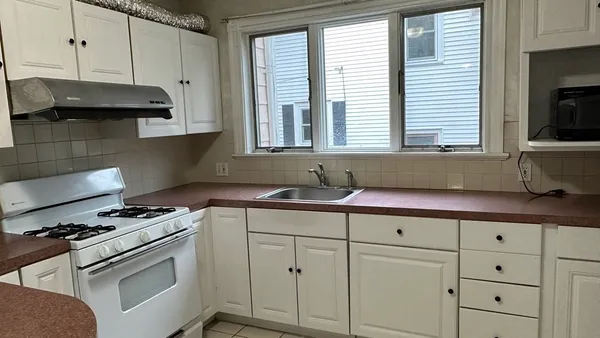 a kitchen with granite countertop a sink a stove and cabinets