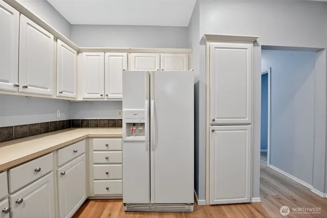 a kitchen with white cabinets and refrigerator