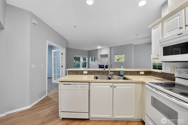 a kitchen with stainless steel appliances granite countertop a sink and cabinets with wooden floor