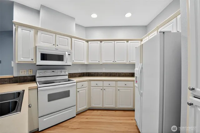 a kitchen with granite countertop white cabinets white stainless steel appliances and sink