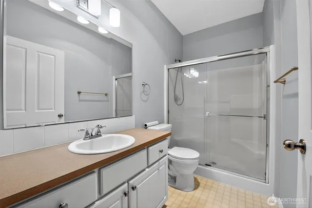 a bathroom with a sink a toilet a mirror and shower