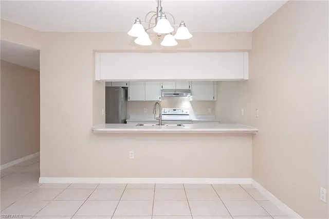 a view of an empty room and chandelier fan