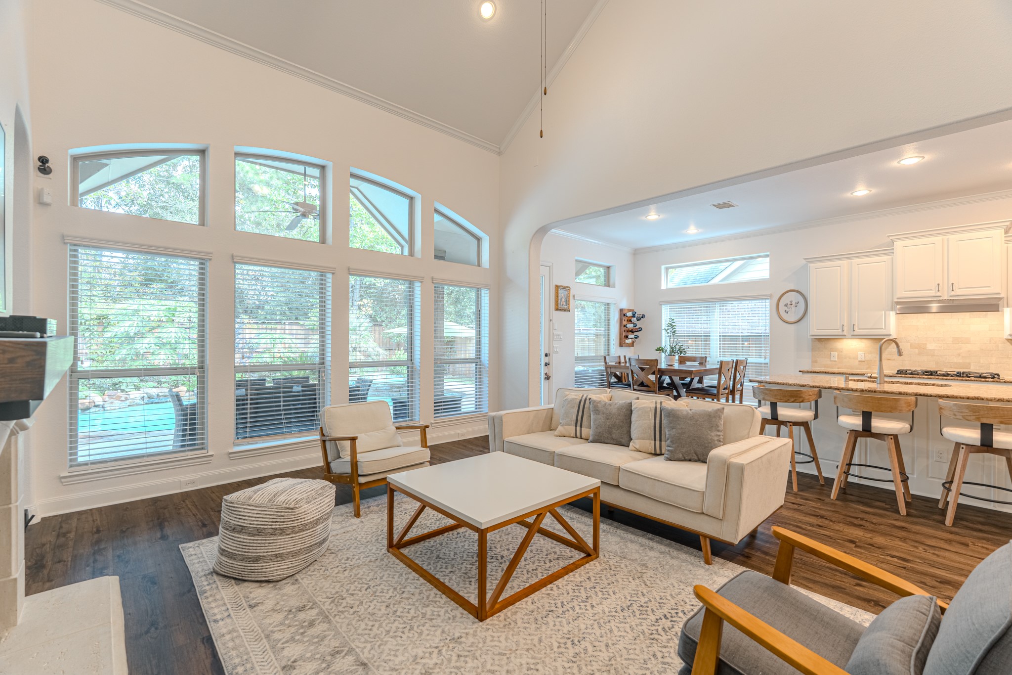 30 Fury Ranch Place The Woodlands, TX 77375 - Photo 22 of 47 This inviting open-concept living space features high ceilings, a modern kitchen with white cabinetry and stainless steel appliances, and a cozy living area with stylish furniture. The room is bright and airy, enhanced by elegant flooring and a staircase leading to an upper level, creating a perfect blend of comfort and sophistication for family living.
