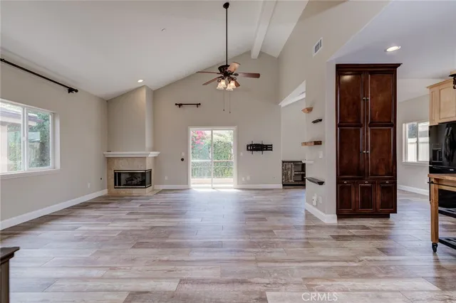 a view of a livingroom with wooden floor a ceiling fan and kitchen space