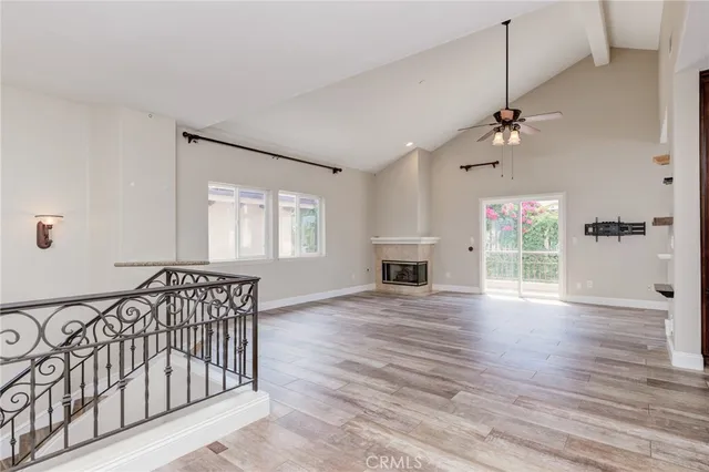 an empty room with wooden floor fan and windows