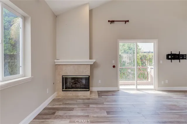a view of an empty room with wooden floor fireplace and a window