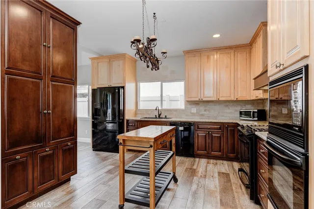 a kitchen with stainless steel appliances granite countertop a refrigerator oven a sink dishwasher and wooden cabinets with wooden floor