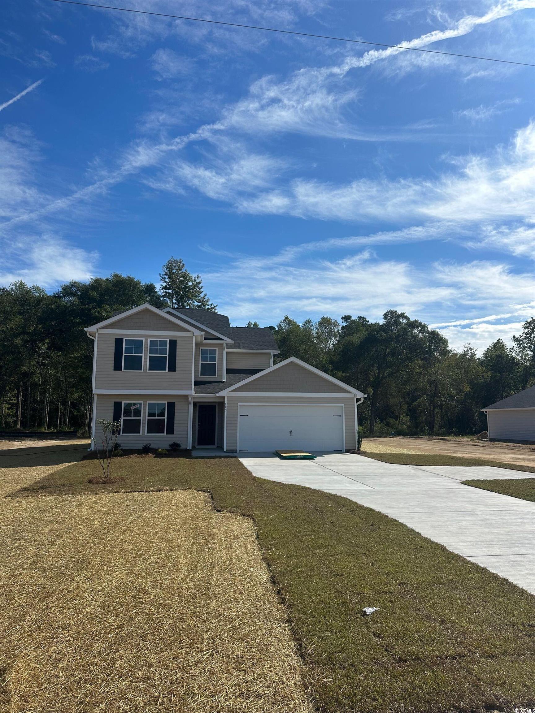 View of front of property with concrete driveway, a front lawn, and an attached garage