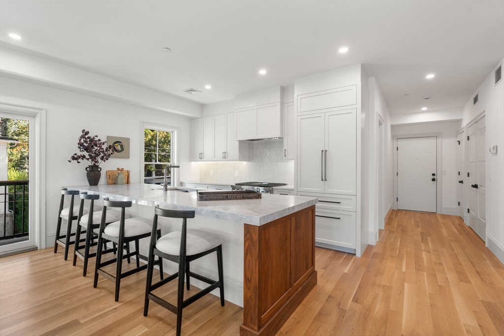69 Williams Street, Unit 3 Boston, MA 02130 - Photo 2 of 22 a kitchen with stainless steel appliances granite countertop a stove top oven a sink dishwasher and a dining table with wooden floor