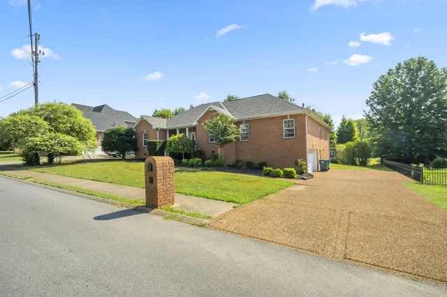 a view of a house with a yard and large tree