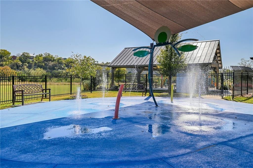 375 Housefinch Loop Leander, TX 78641 - Photo 27 of 28 A dynamic splash pad features interactive water elements under a protective shade sail canopy.