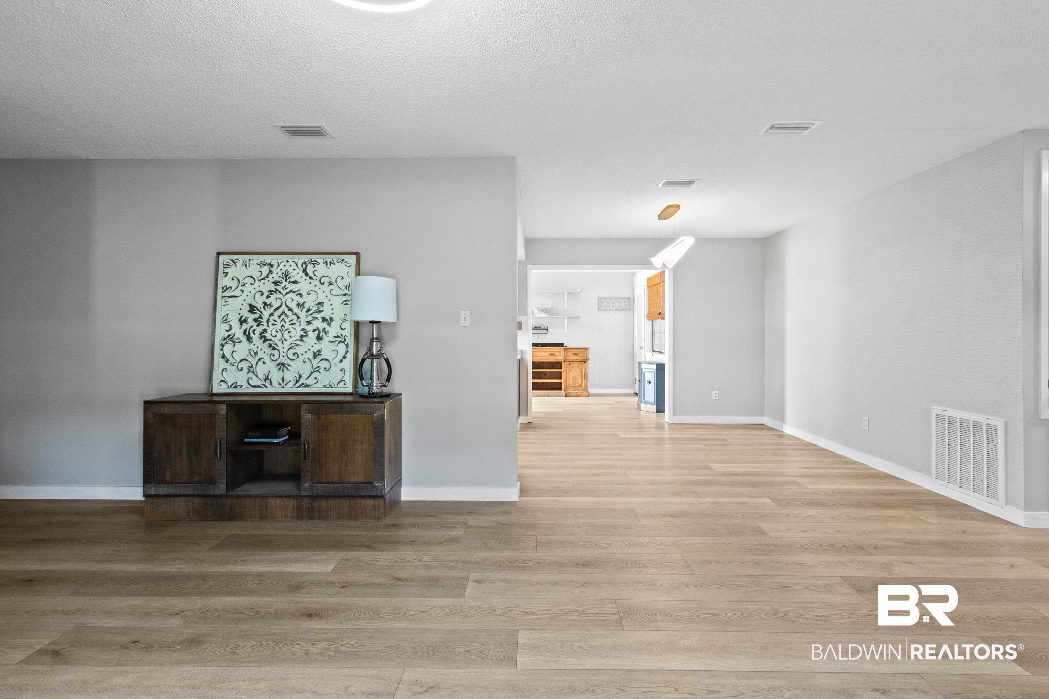 524 Ariel Avenue Foley, AL 36535 - Photo 8 of 37 Expansive room featuring wood-finish flooring, light gray wall paint, white baseboards, and an overhead lighting fixture