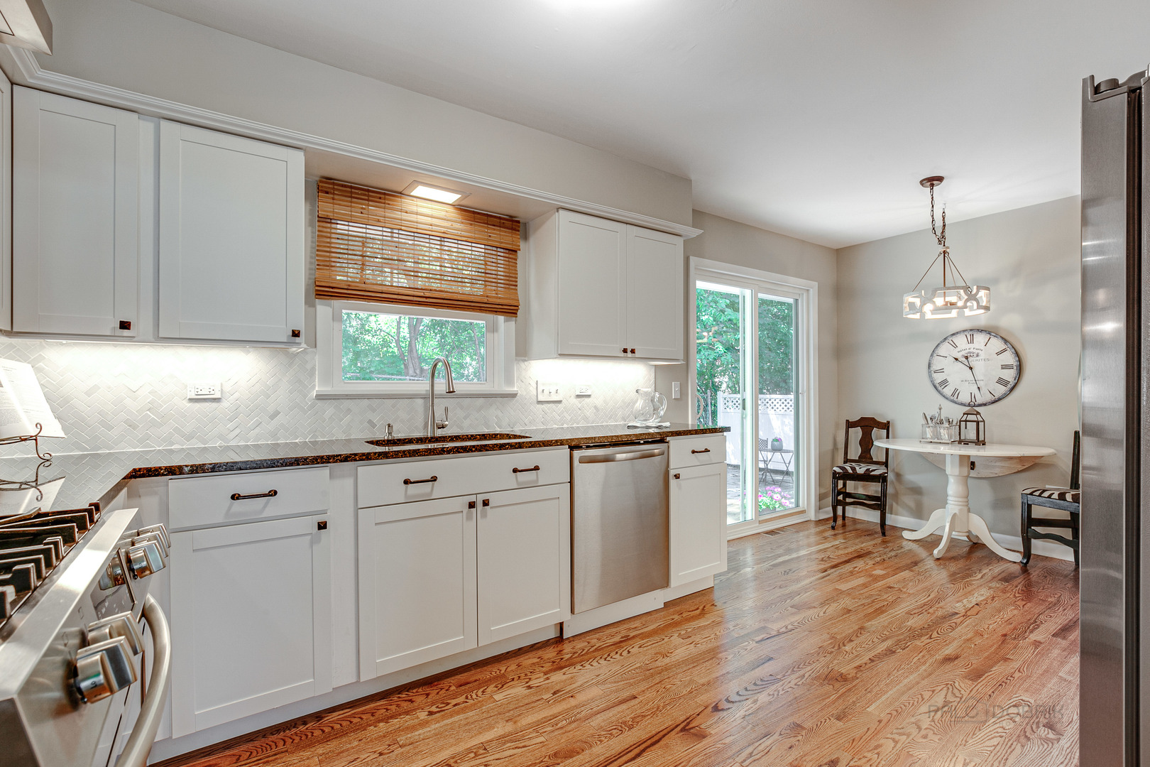 235 Waverly Road Barrington, IL 60010 - Photo 9 of 26 a kitchen with granite countertop a stove a sink a dining table and chairs with wooden floor