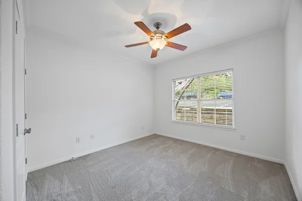 an empty room with ceiling fan and window