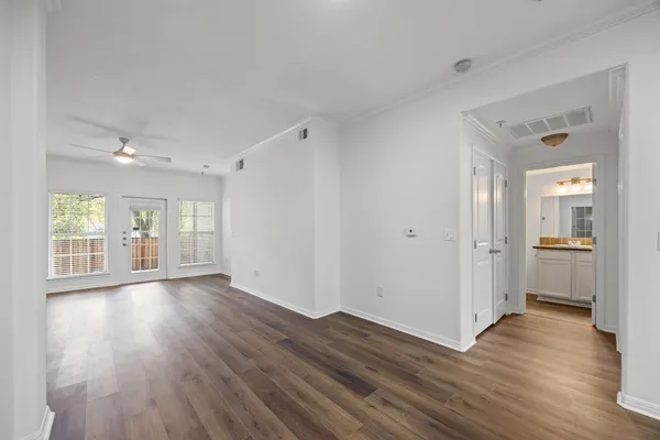 a view of an empty room with wooden floor and a window