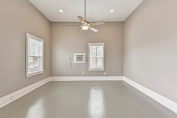 an empty room with windows and ceiling fan