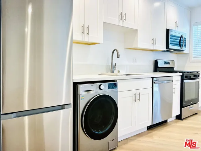 a kitchen with white cabinets sink and stainless steel appliances