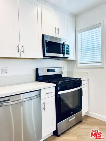 a kitchen with stainless steel appliances granite countertop a stove a microwave and white cabinets