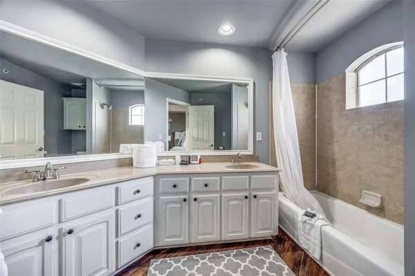 a bathroom with a double vanity sink a mirror a bathtub and next to a window