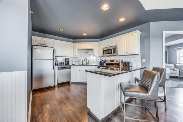 a kitchen with granite countertop white cabinets and stainless steel appliances