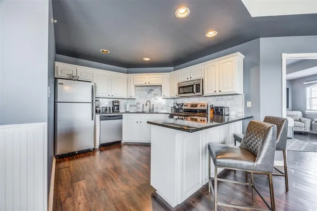 a kitchen with granite countertop white cabinets and stainless steel appliances