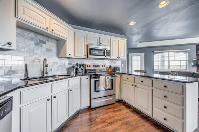 a kitchen with granite countertop white cabinets and white appliances