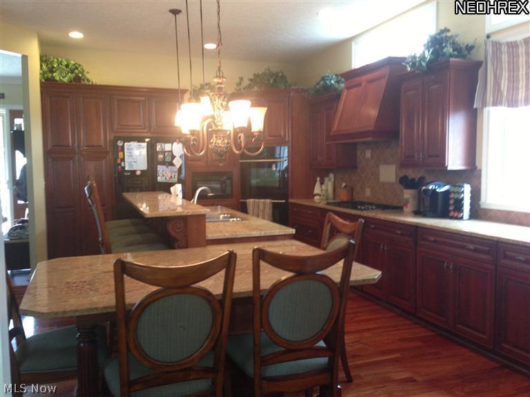 452 Forestview Road Bay Village, OH 44140 - Photo 3 of 24 Hardwood floors and gleaming granite counters in large open kitchen with custom cabinets, built-in appliances, breakfast bar and dining table