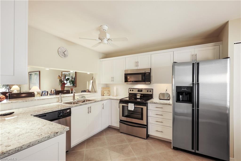 6740 Dennis Circle, Unit B103 Naples, FL 34104 - Photo 3 of 16 a kitchen with stainless steel appliances kitchen island granite countertop a refrigerator a sink a stove a oven with white cabinets