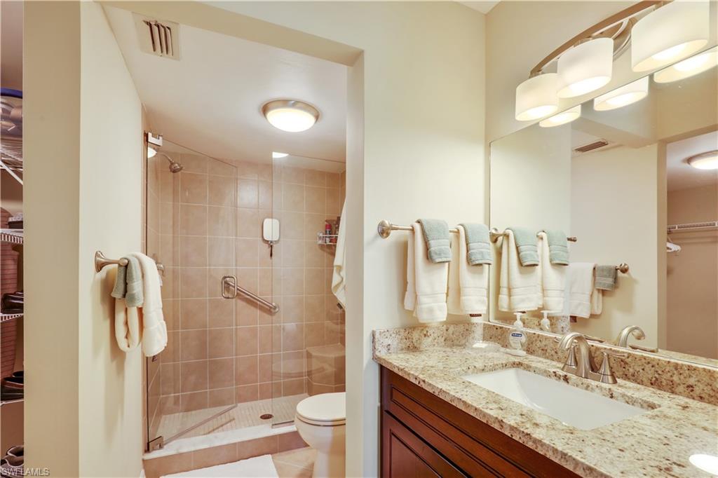 6740 Dennis Circle, Unit B103 Naples, FL 34104 - Photo 7 of 16 a bathroom with a granite countertop sink a toilet a mirror and shower