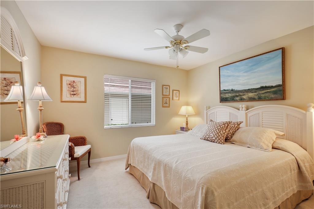 6740 Dennis Circle, Unit B103 Naples, FL 34104 - Photo 8 of 16 a bedroom with a bed and a chandelier